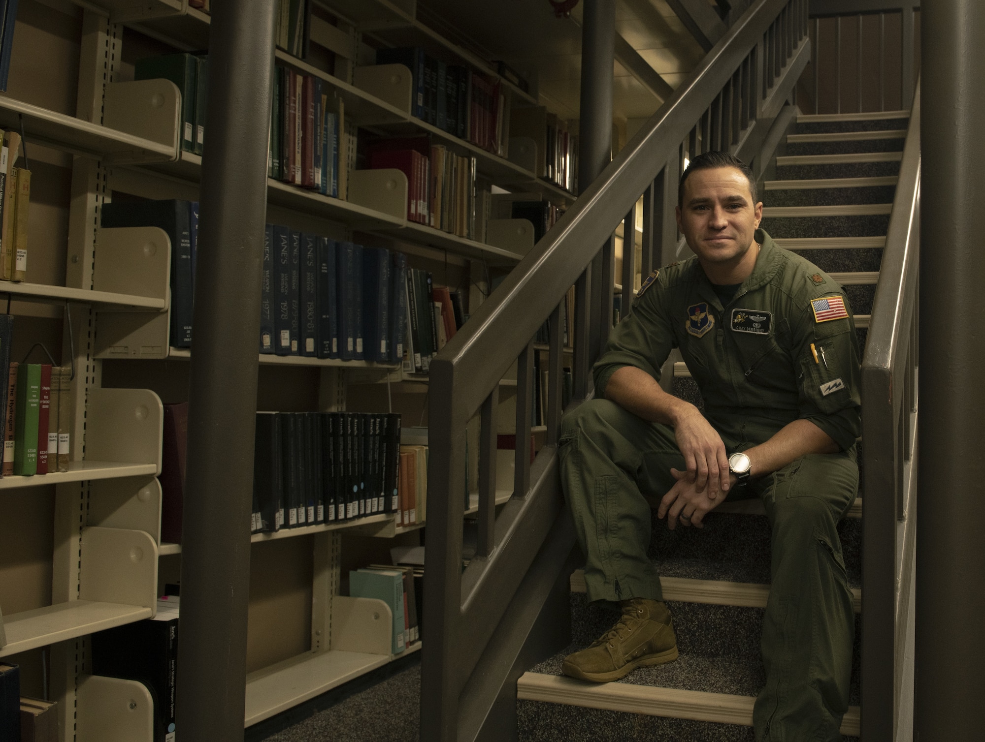 Maj. Chay Derbigny sits on a staircase in the Air University Library.