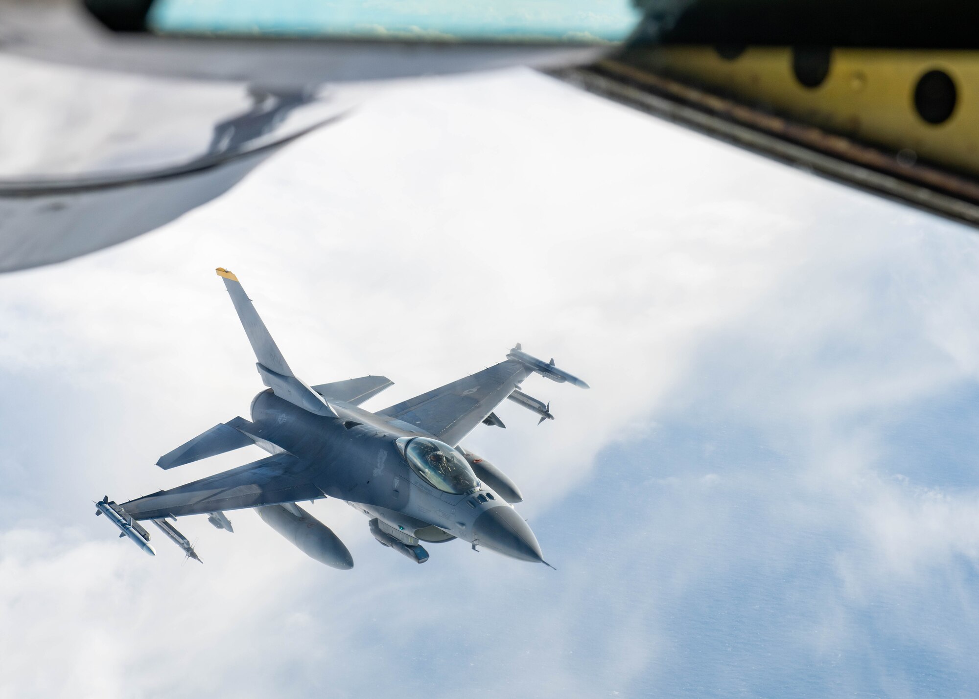 A jet flies in behind a refueling plane