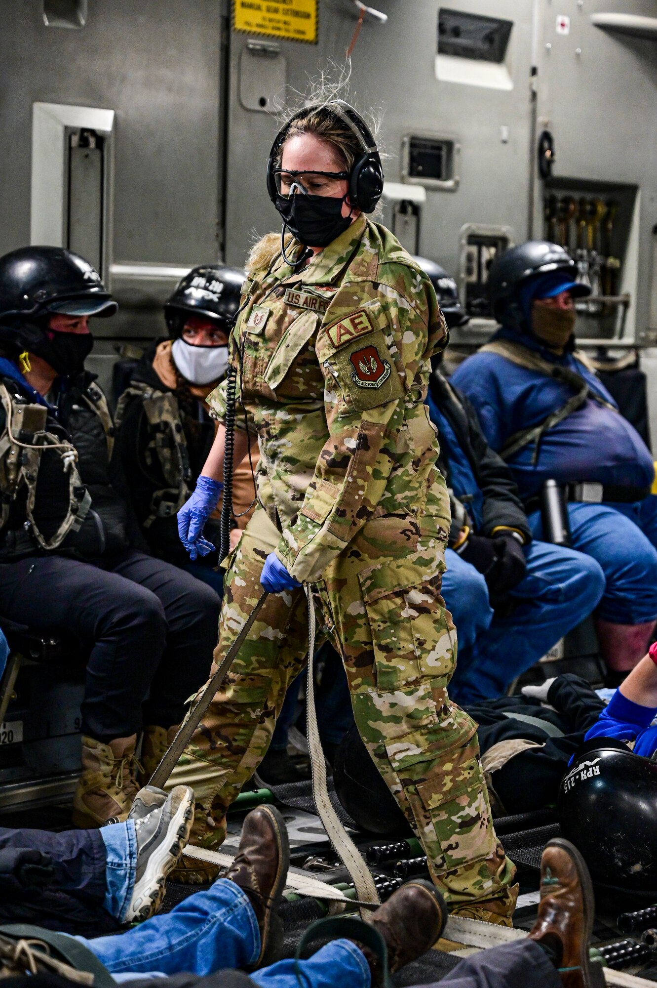 A person assists in boarding patients with simulated injuries onto a C-17 Globemaster III