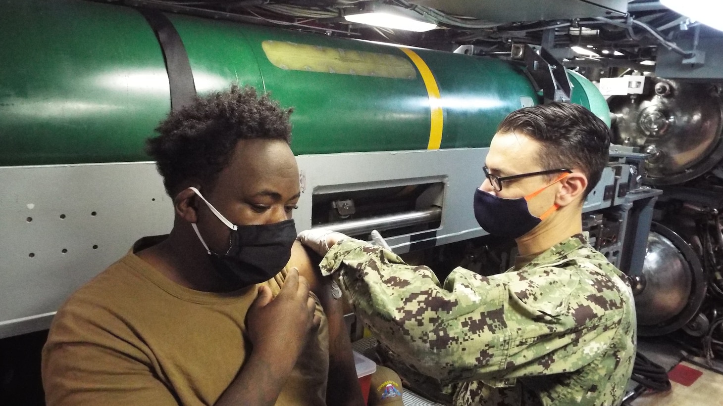 Hospital Corpsman 1st Class Nash Bovard, right, administers a COVID-19 vaccine booster to Culinary Specialist (Submarine) 3rd Class Zhabaron Brown during a shot exercise.