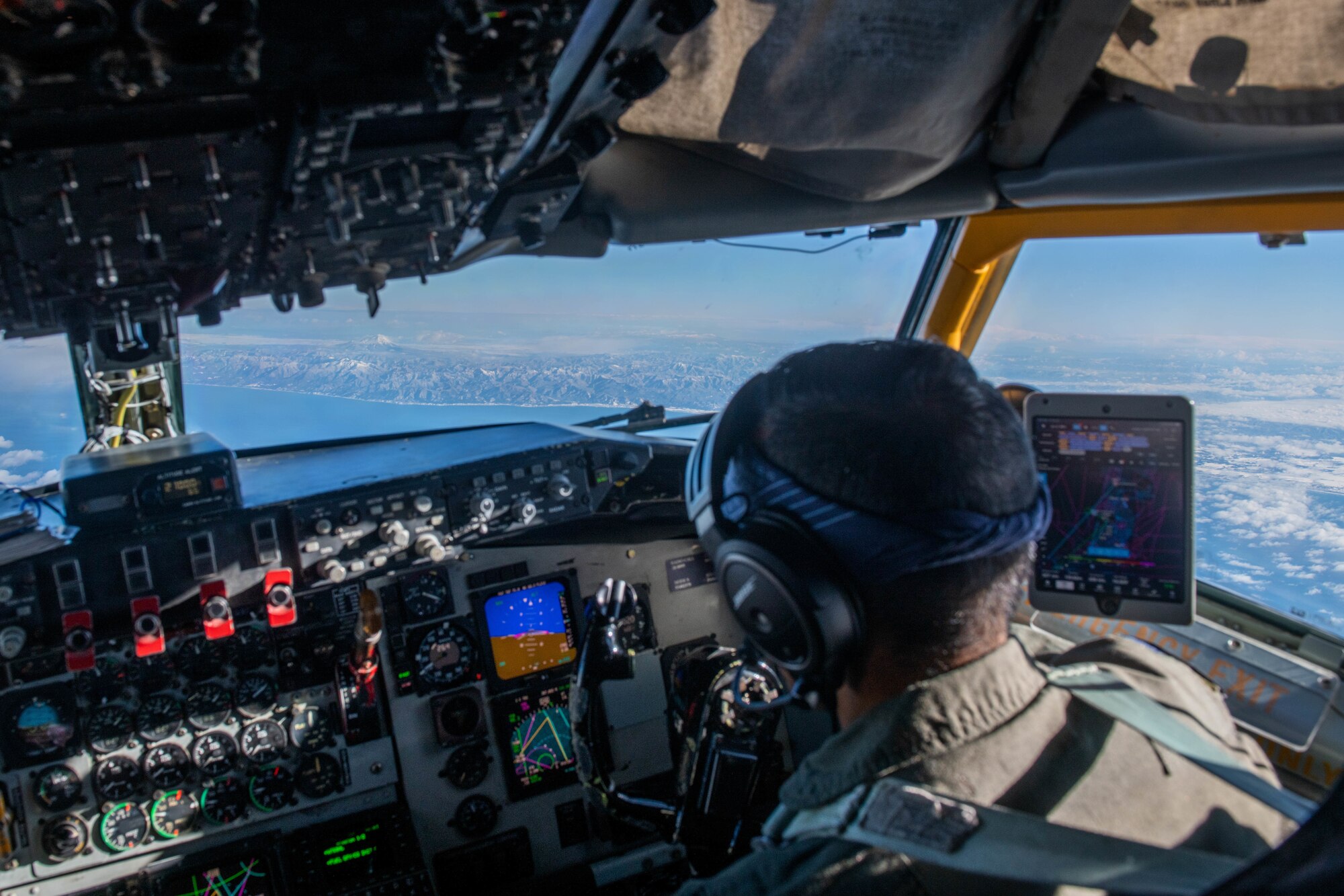 A pilot steers the plane with mountains outside the window