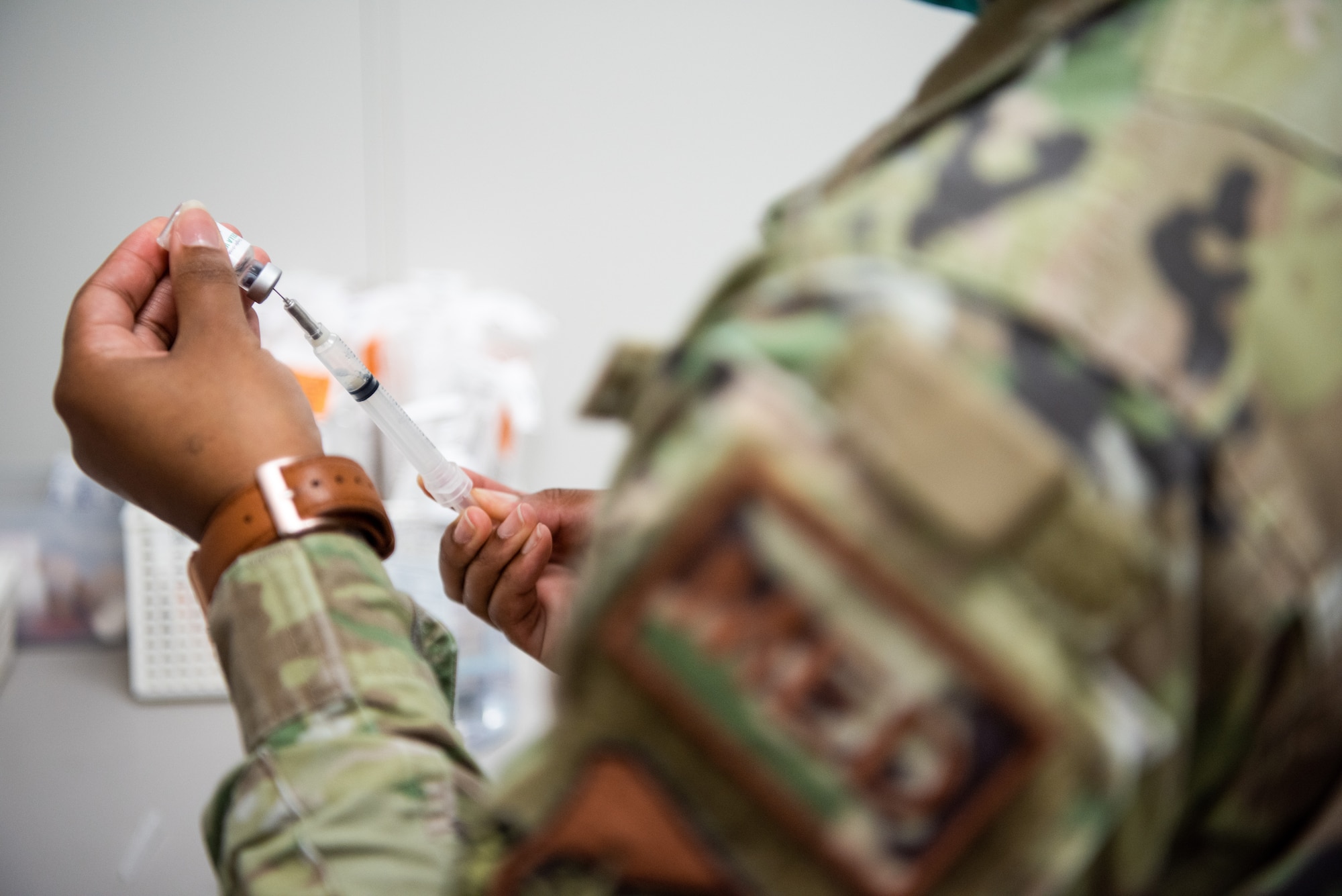 A medical technician draws a vaccine into a syringe.