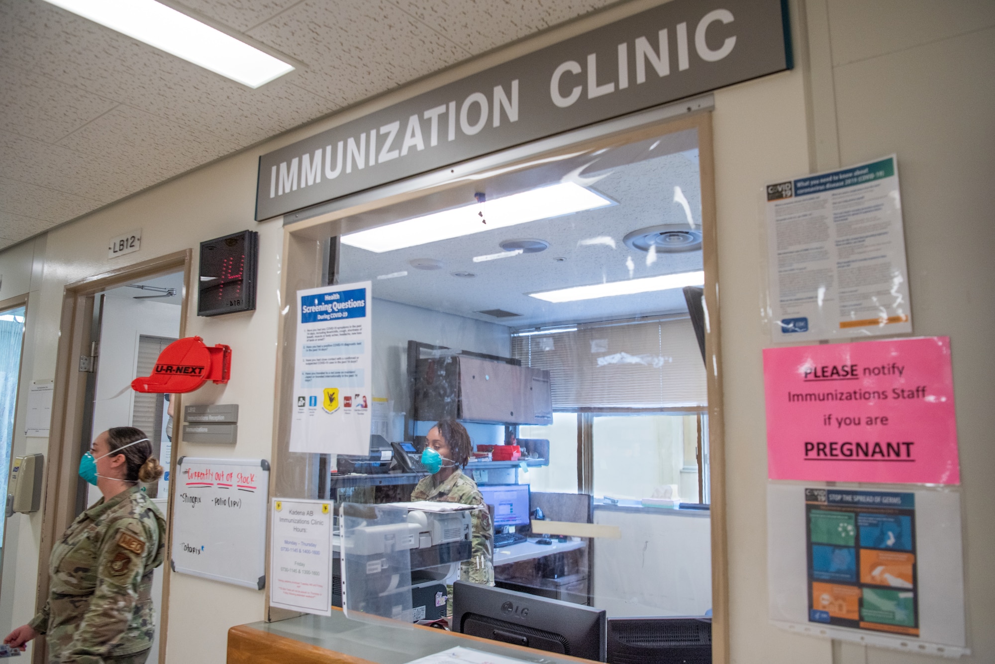 Two medical technicians walk from behind the front desk of the clinic