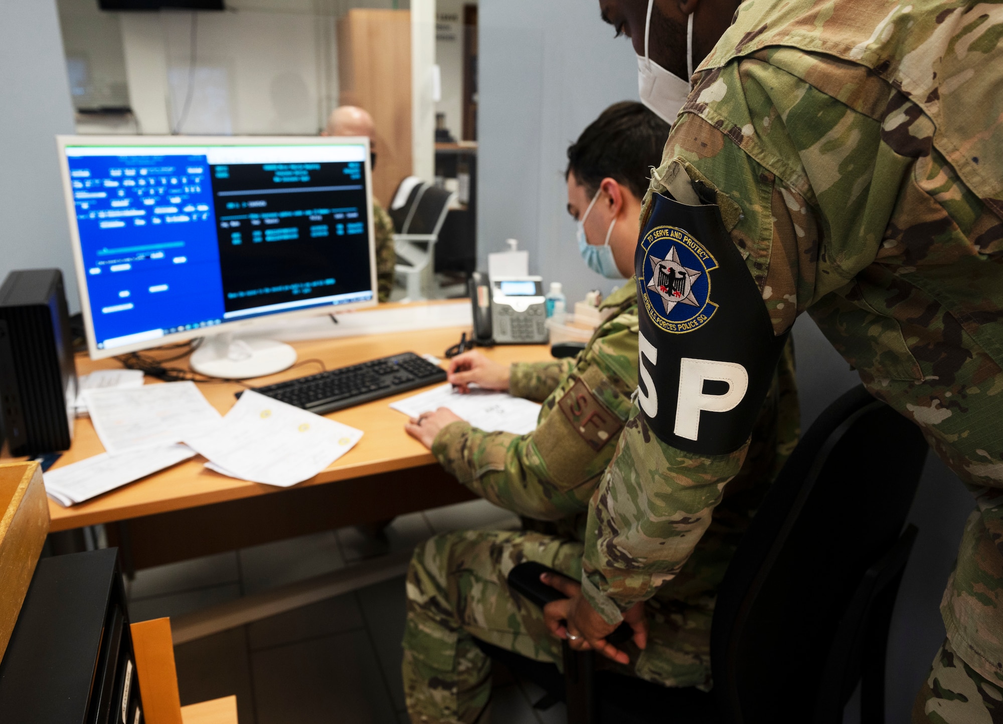 A 569th United States Forces Police Squadron Vehicle Registration clerks look over a customer’s paperwork at Kapaun Air Station, Germany, Jan. 24, 2022. The 569 USFPS created two QR codes to increase efficiency and save time. (U.S. Air Force photo by Senior Airman Thomas Karol)