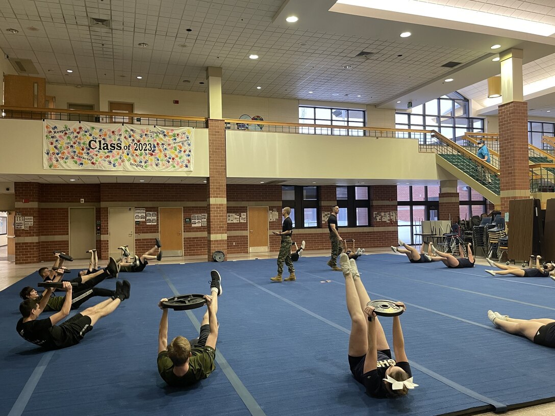 U.S. Marine Corps recruiters monitoring physical training the students conduct.