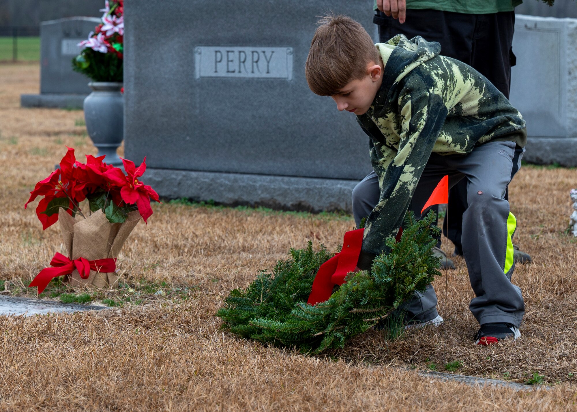 A member of the local community places a wreath at a headstone during the Wreaths Across America ceremony, at the Pikeville Cemetery in Pikeville, North Carolina, Dec. 19, 2021.