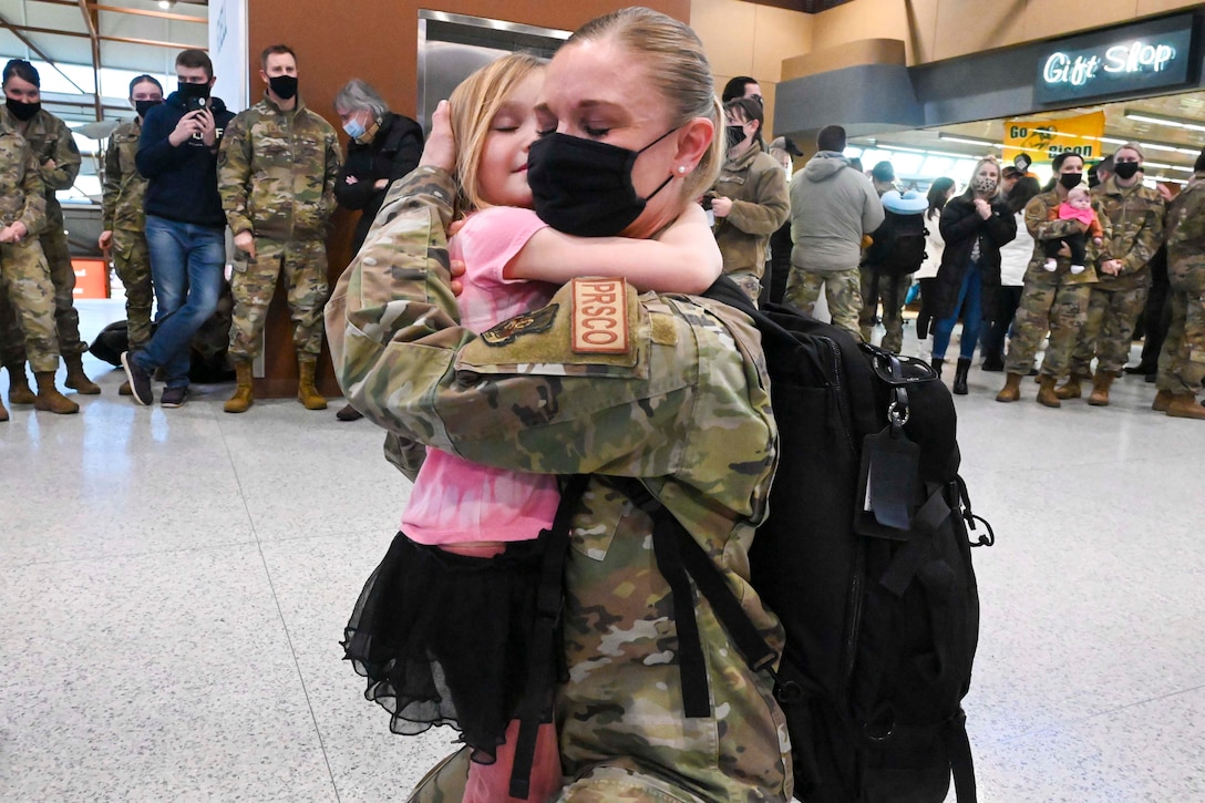 An airman hugs a child.