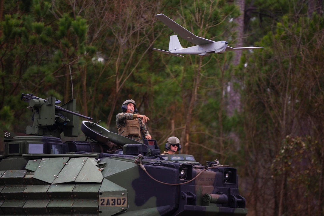 A Marine launches a small unmanned aircraft from a military vehicle.