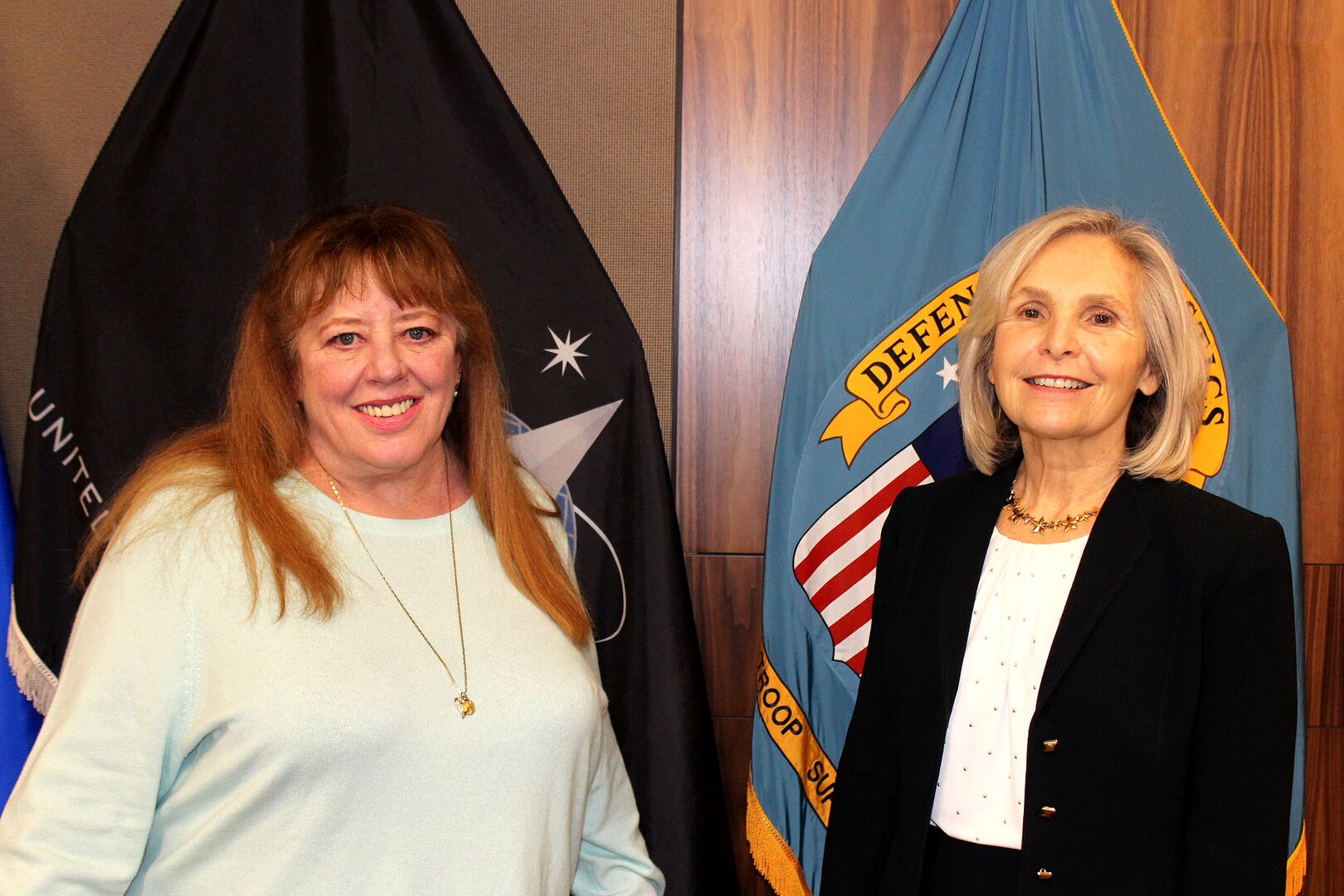 Two women stand in front of flags