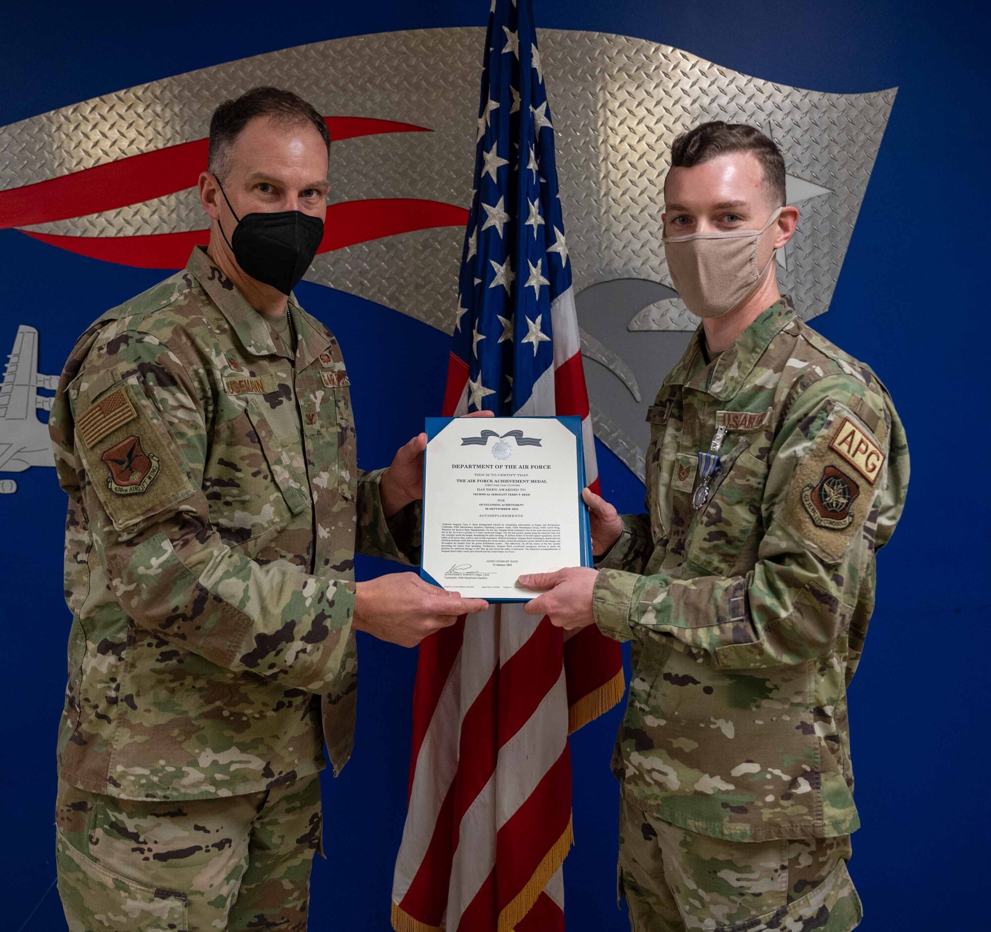 Col. Matt Husemann, 436th Airlift Wing commander (left), presents an Air Force Achievement Medal to Tech. Sgt. Terry Reed, 436th Maintenance Squadron, Operating Location Alpha, repair and reclamation craftsman, at Westover Air Reserve Base, Massachusetts, Jan. 25, 2022. Reed was presented the medal for witnessing a fire in a C-5 Isochronal Maintenance Dock and performing heroic actions to extinguish it. (U.S. Air Force photo by Senior Airman Faith Schaefer)