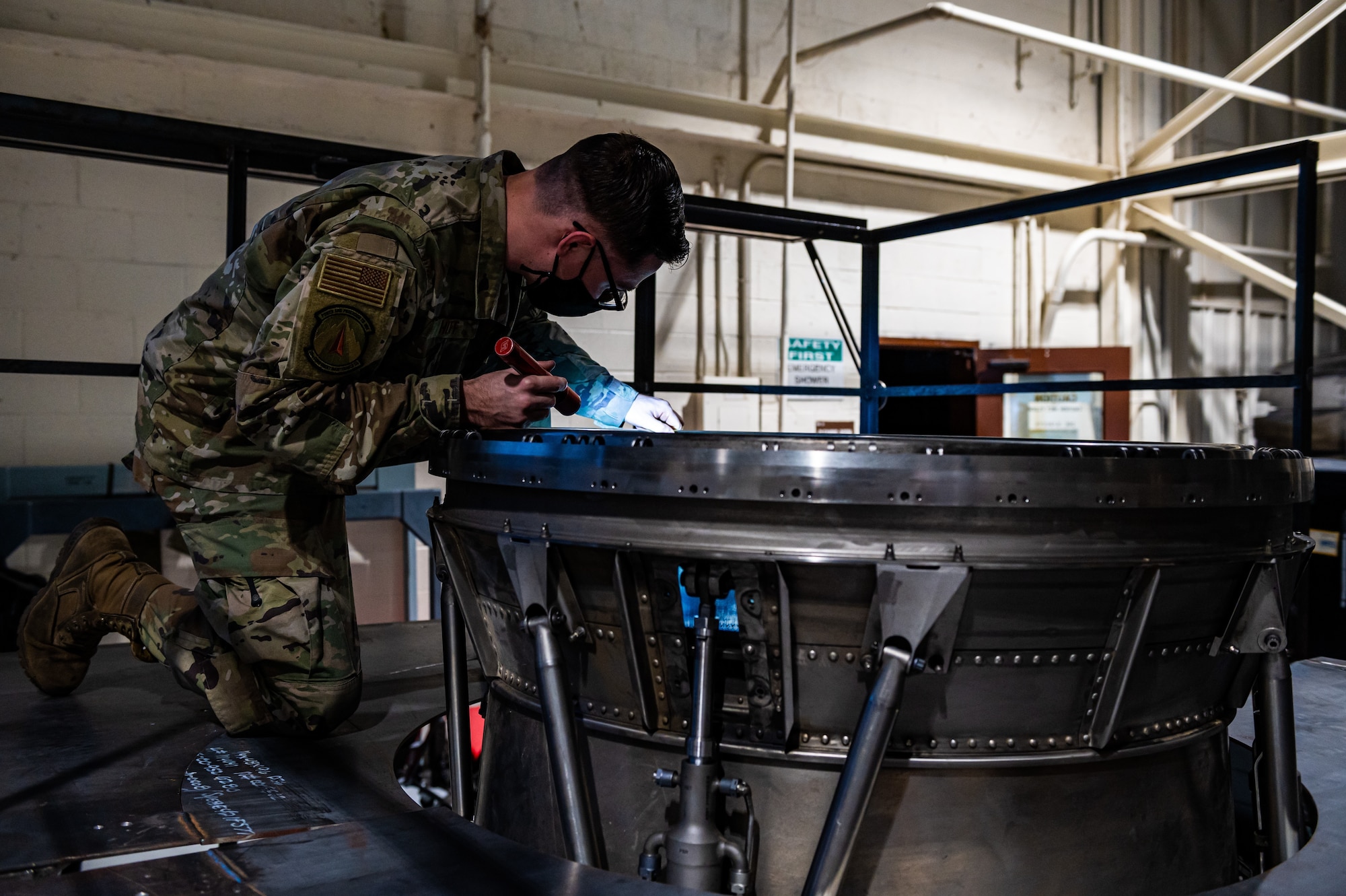 Photo of Airman looking into exhaust assembly.