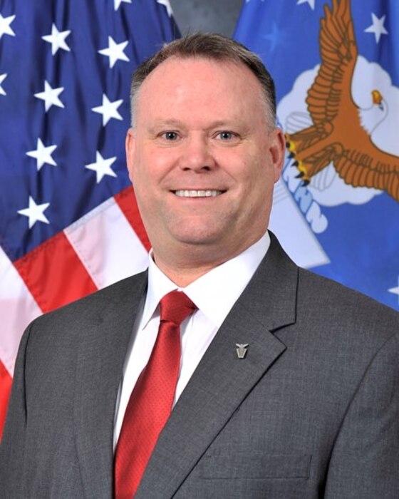 Mr. Aldridge is standing in front of an American flag