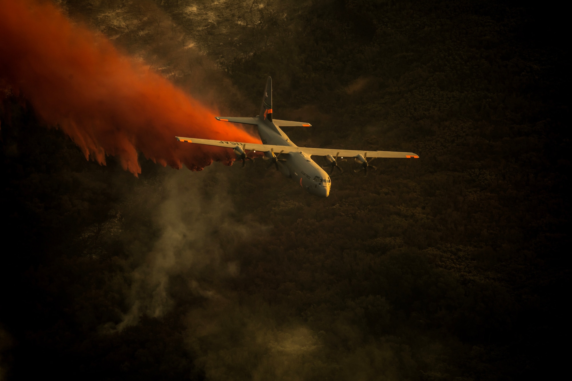 A U.S. Air National Guard C-130J equipped with the MAFFS 2 (Modular Airborne Fire Fighting System) drops a line of Phos-Chek on the Thomas Fire in the hills above the city of Santa Barbara Dec. 13, 2017. The C-130J from the 146th Airlift Wing has been supporting CAL FIRE’s efforts to battle the Thomas Fire raging in Southern California. (U.S. Air National Guard photo illustration by: Master Sgt. Nieko Carzis.)