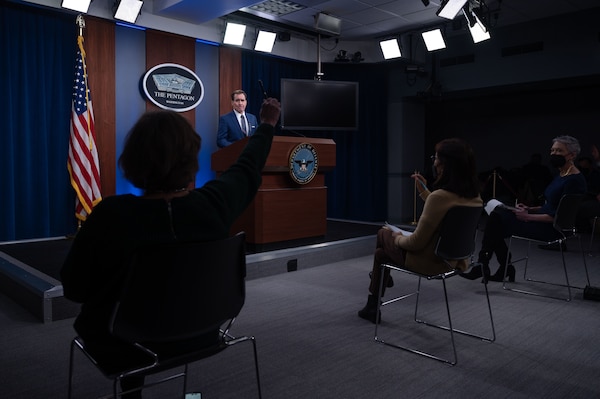 A reporter raises her hand to be recognized at a Pentagon news conference.