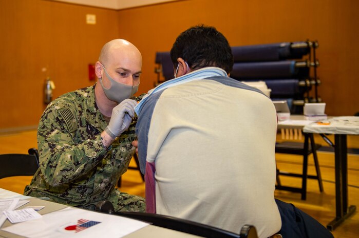 220128-N-SI601-1070 YOKOSUKA, Japan (Jan. 28, 2022) Hospital Corpsman 2nd Class Andrew Quigley, from Wichita, Kansas, assigned to the U.S. Navy’s forward-deployed aircraft carrier USS Ronald Reagan (CVN 76), administers a COVID-19 vaccination booster to a Japanese base employee on Commander, Fleet Activities Yokosuka. Ronald Reagan, the flagship of Carrier Strike Group 5, provides a combat-ready force that protects and defends the United States, and supports alliances, partnerships and collective maritime interests in the Indo-Pacific region. (U.S. Navy photo by Mass Communication Specialist 3rd Class Daniel G. Providakes)