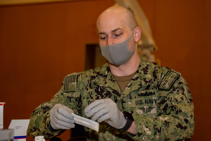 220128-N-SI601-1019 YOKOSUKA, Japan (Jan. 28, 2022) Hospital Corpsman 2nd Class Andrew Quigley, from Wichita, Kansa, assigned to the U.S. Navy’s forward-deployed aircraft carrier USS Ronald Reagan (CVN 76), prepares bandages for administering COVID-19 vaccination boosters on Commander, Fleet Activities Yokosuka. Ronald Reagan, the flagship of Carrier Strike Group 5, provides a combat-ready force that protects and defends the United States, and supports alliances, partnerships and collective maritime interests in the Indo-Pacific region. (U.S. Navy photo by Mass Communication Specialist 3rd Class Daniel G. Providakes)