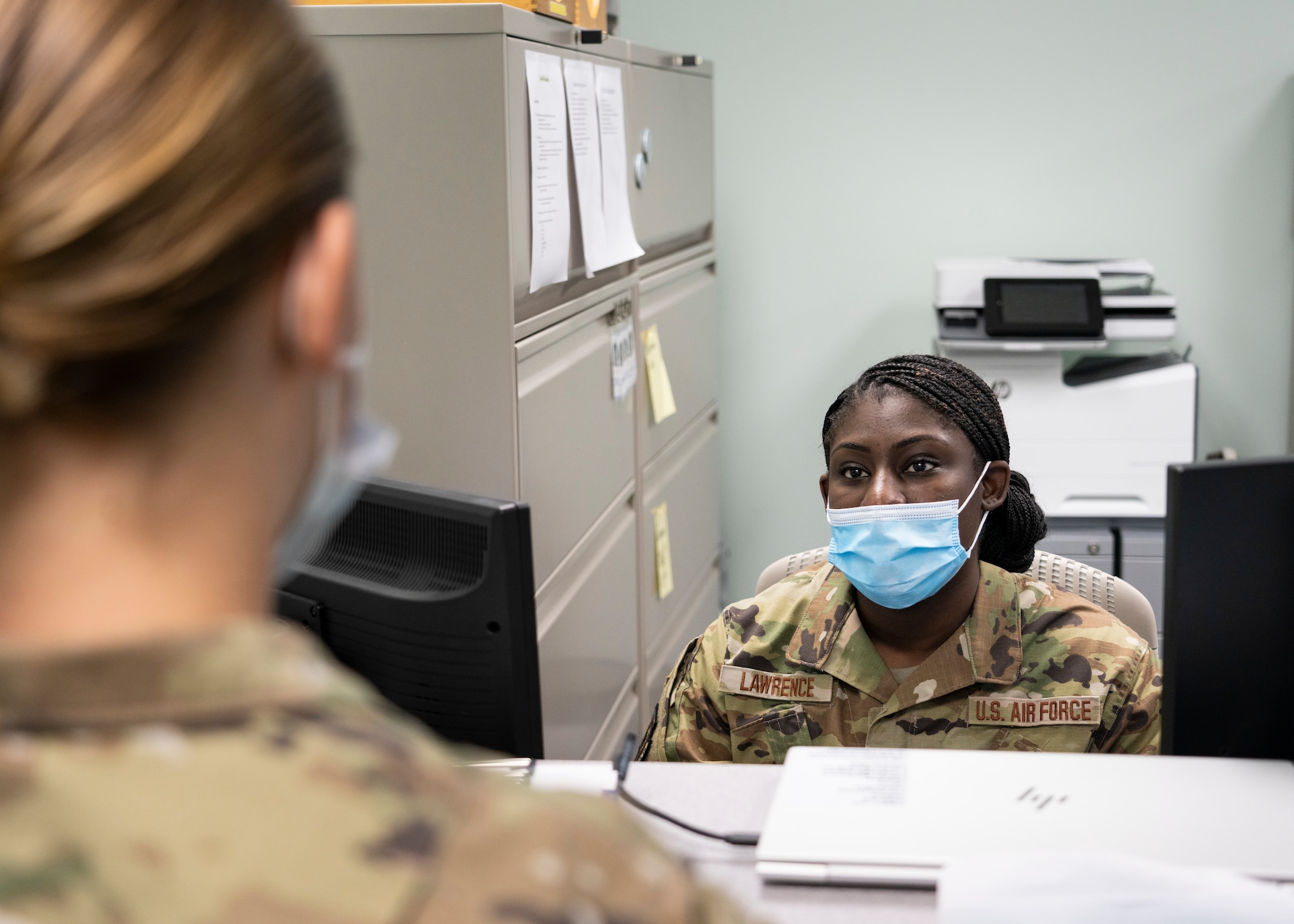 Airman speaks to other Airman behind counter.