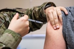 A medical technician administers a COVID-19 vaccine to a patient.