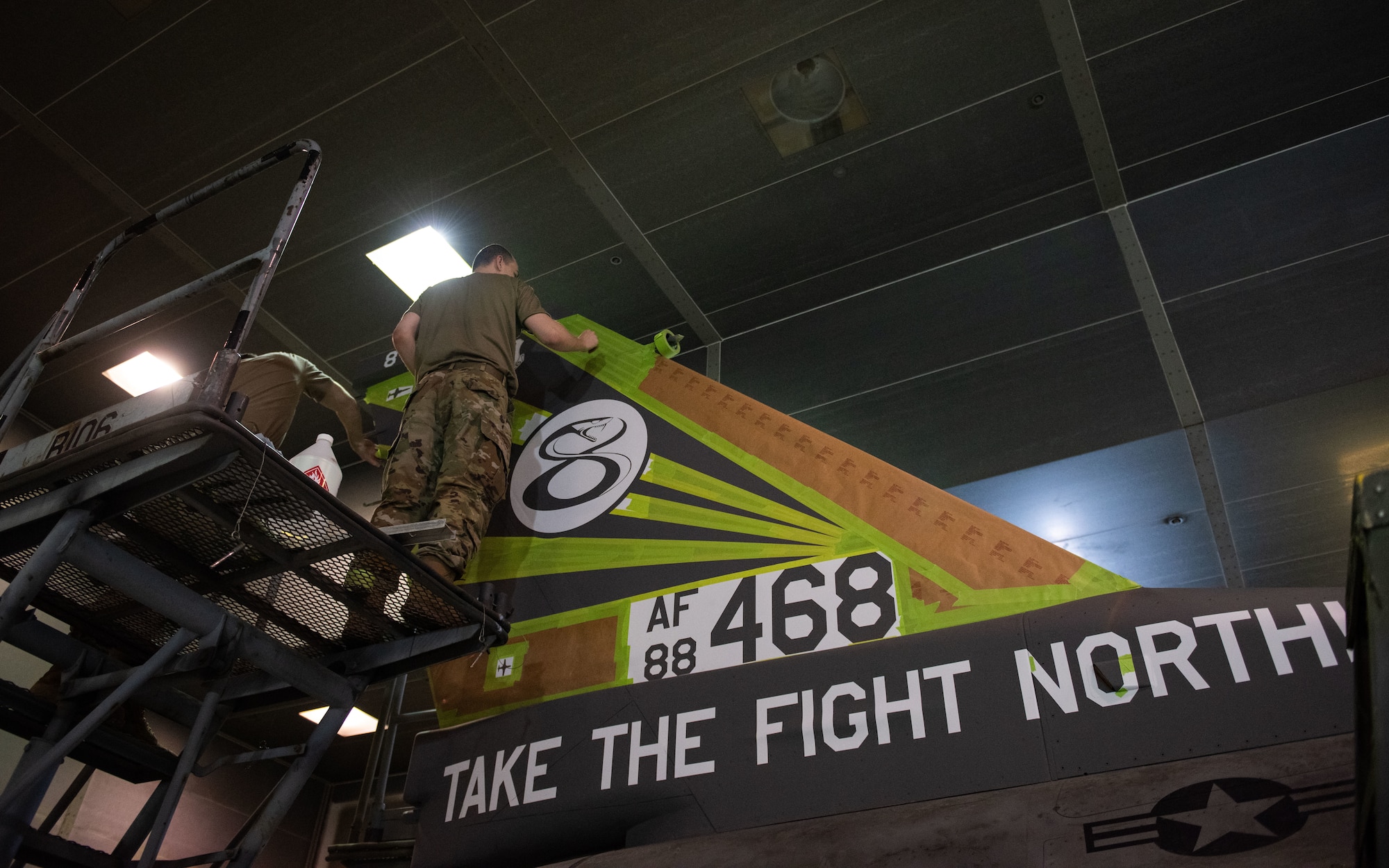 Airmen assigned to the 8th Maintenance Squadron aircraft structural maintenance shop work together to apply stencils for the tail flash of the 8th Operations Group’s F-16 Fighting Falcon