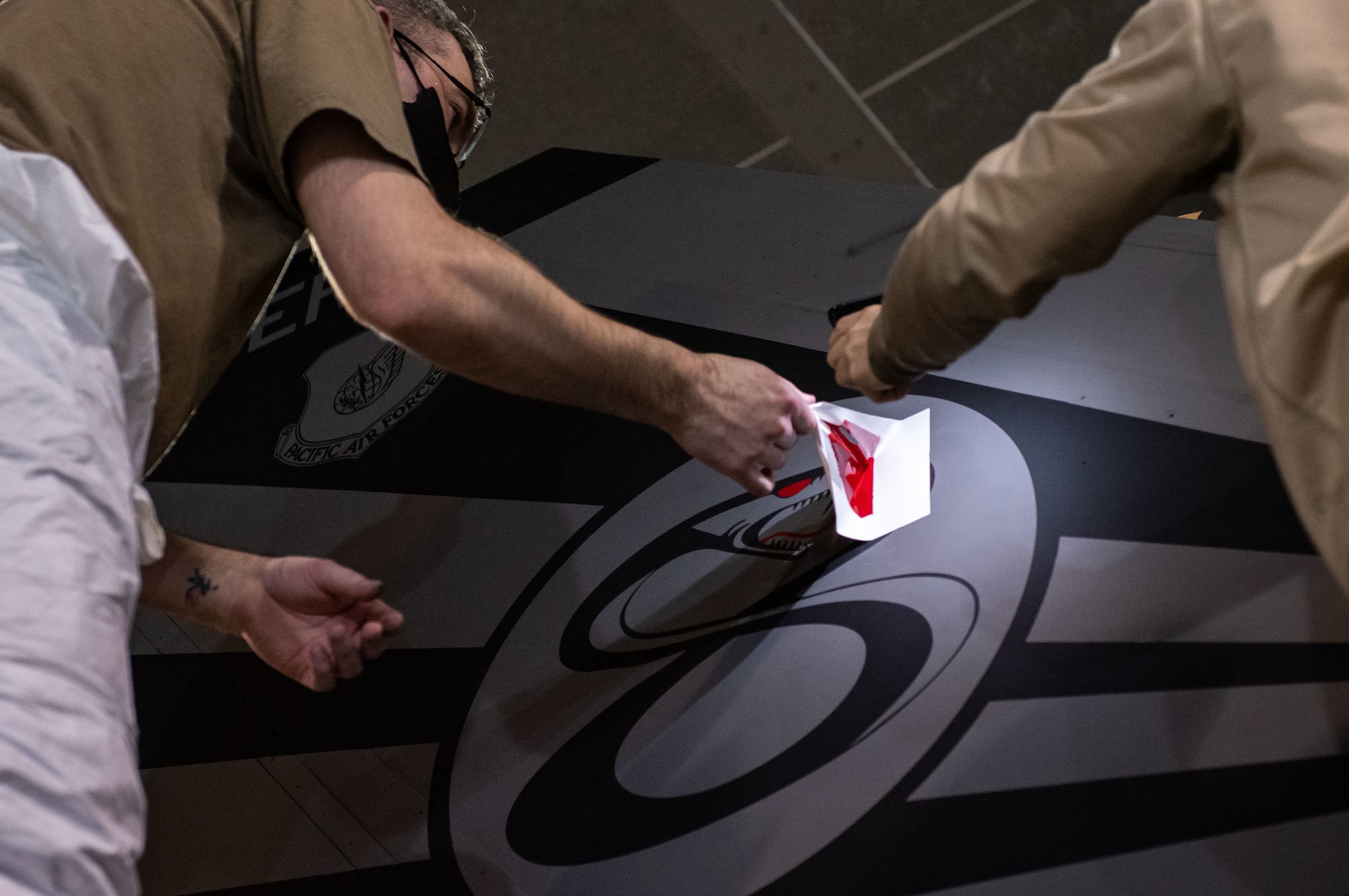 Tech. Sgt. David Lamb, 8th Maintenance Squadron noncommissioned officer in charge of aircraft structural maintenance, left, removes a stencil from an F-16 Fighting Falcon
