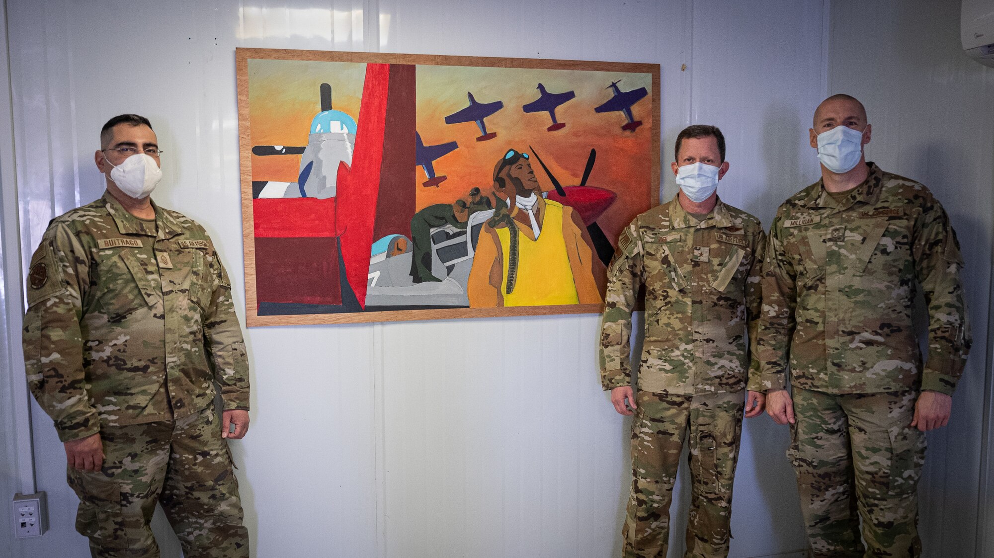 U.S. Air Force Brig. Gen. Christopher Sage, 332d Air Expeditionary Wing commander, center and Chief Master Sgt. Sean Milligan, command chief, right, stand with Senior Master Sgt. Fernando Buitrago, 332d Expeditionary Logistics Readiness Squadron senior enlisted leader inside the Red Tail Center of Excellence as they pose with the finished pieces of the Legacy Project, January 26, 2022, Southwest Asia.  The Legacy Project is a set of two paintings depicting the heritage and culture of the Tuskegee Airmen and the 332d AEW culture today, bringing past and present together. (U.S. Air Force photo by Master Sgt. Christopher Parr)