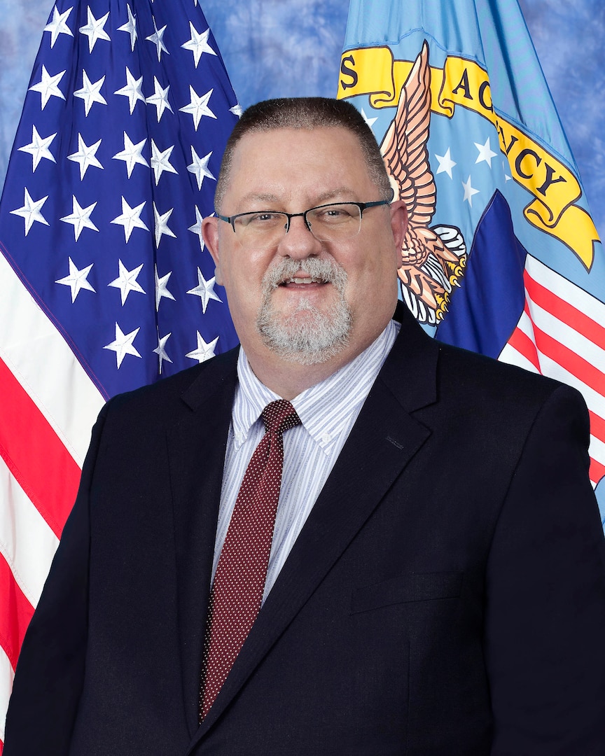 Portrait of man with flags in the background.
