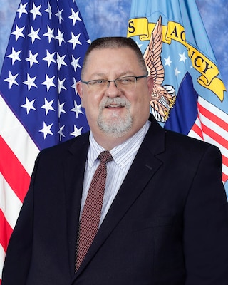 Portrait of man with flags in the background.
