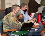 Transition team members discuss MHS GENESIS implementation in the Emergency Operations Center at Brooke Army Medical Center, Joint Base San Antonio-Fort Sam Houston, Texas, Jan. 22, 2022. The EOC was manned by clinical and support teams from across the organization working around the clock to help ensure a smooth transition to the new electronic health record system.