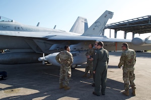Aircrew from the U.S. Navy Electronic Attack Squadron 139 (VAQ-139) teach Airmen of the 114th Space Control Squadron, Florida Air National Guard, about the capabilities of the EA-18G Growler and the ALQ-99 Tactical Jamming System at Cape Canaveral Space Force Station, Florida, in December 2021.