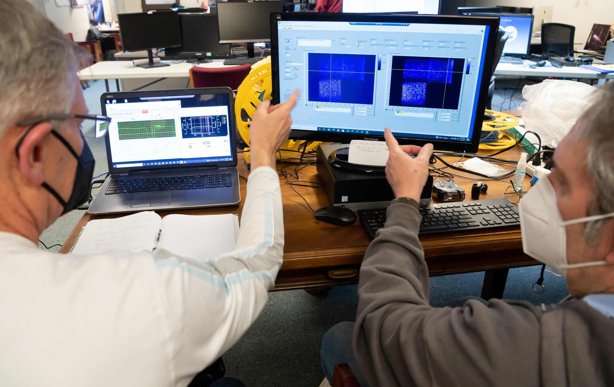 From left, Dr. Tom Jenkins, president of MetroLaser, Inc., and Regis Morgan, senior engineer with MetroLaser, observe the visual display of data during a test of the company's setup to non-invasively measure the unsteady, 3D velocity field of a jet plume from a stationary aircraft engine, Nov. 18, 2021, at the Propulsion Research Facility.