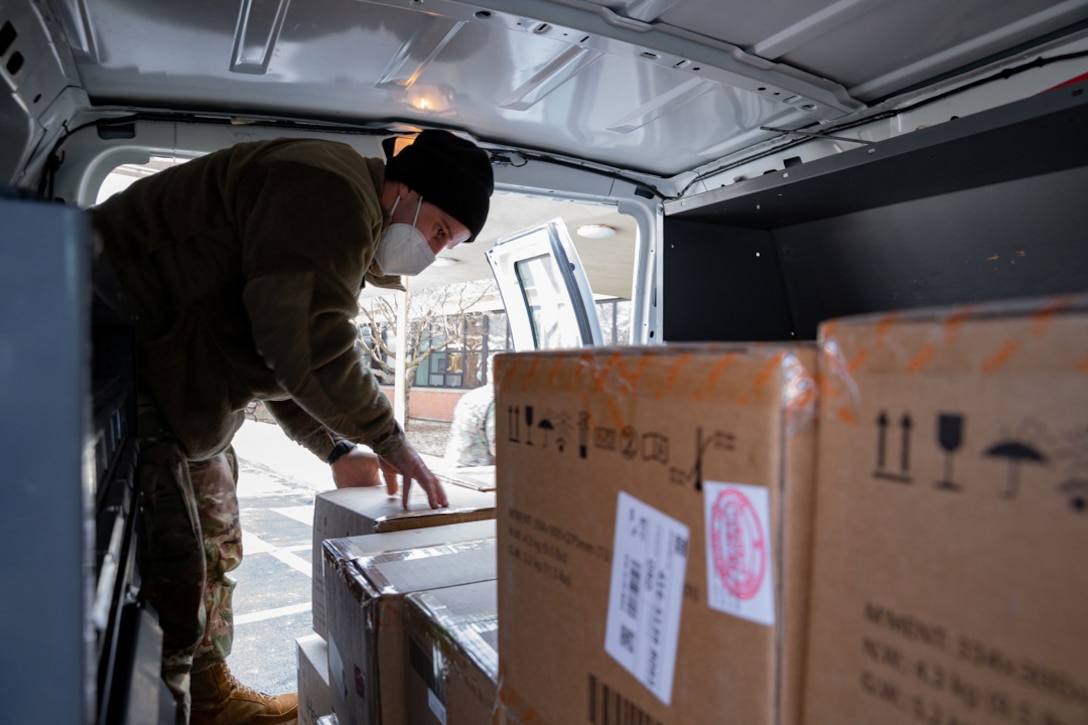 A soldier loads boxes into a van.