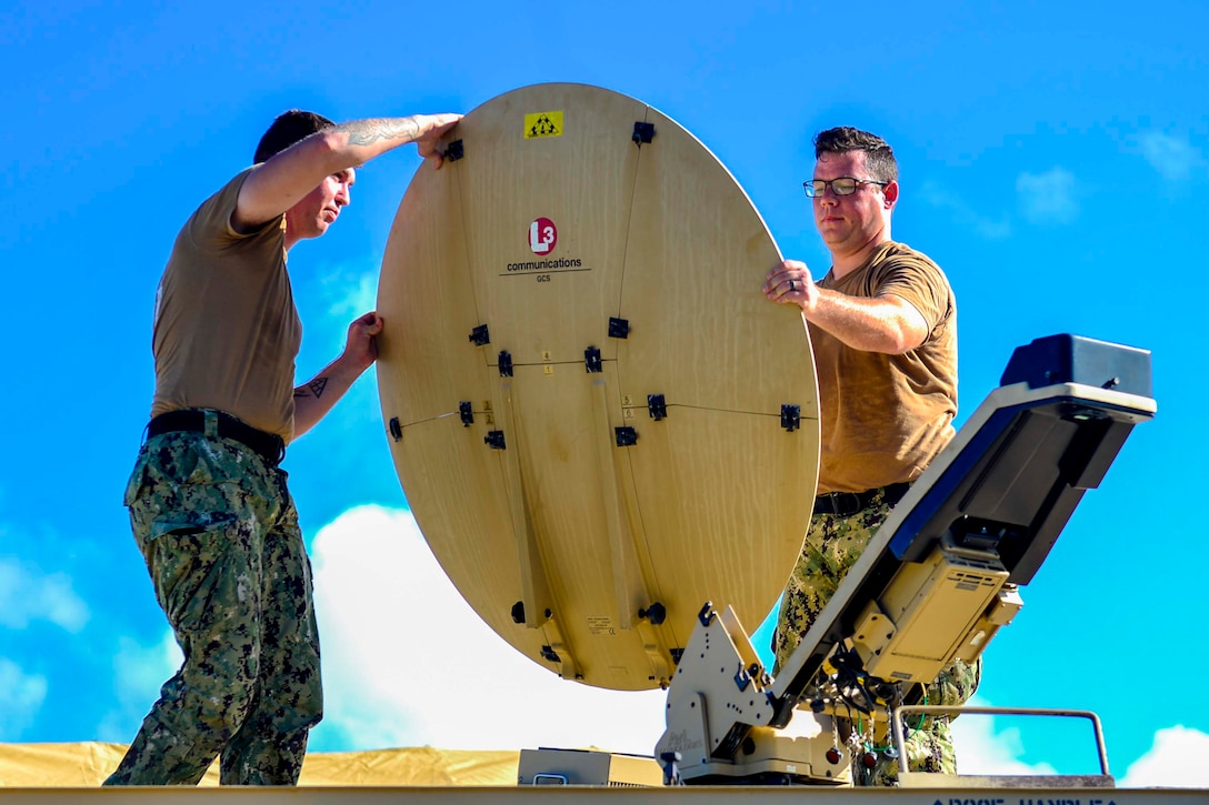 Two sailors set up a satellite.