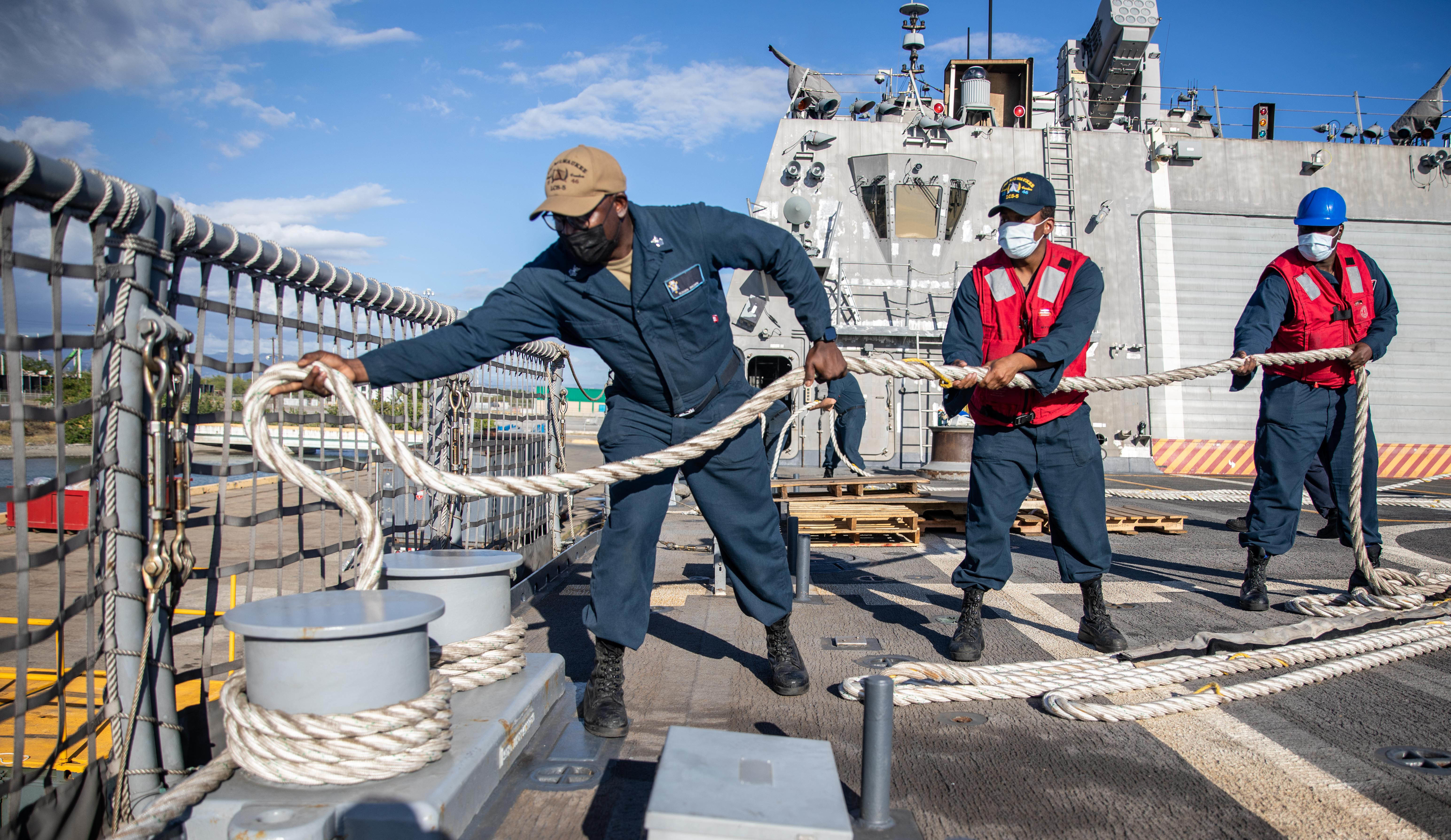 Sailors handle line on the flight deck of USS Milwaukee (LCS 5) as the ship departs Ponce, Puerto Rico, after completing a planned maintenance availability (PMAV), Jan. 26, 2022.