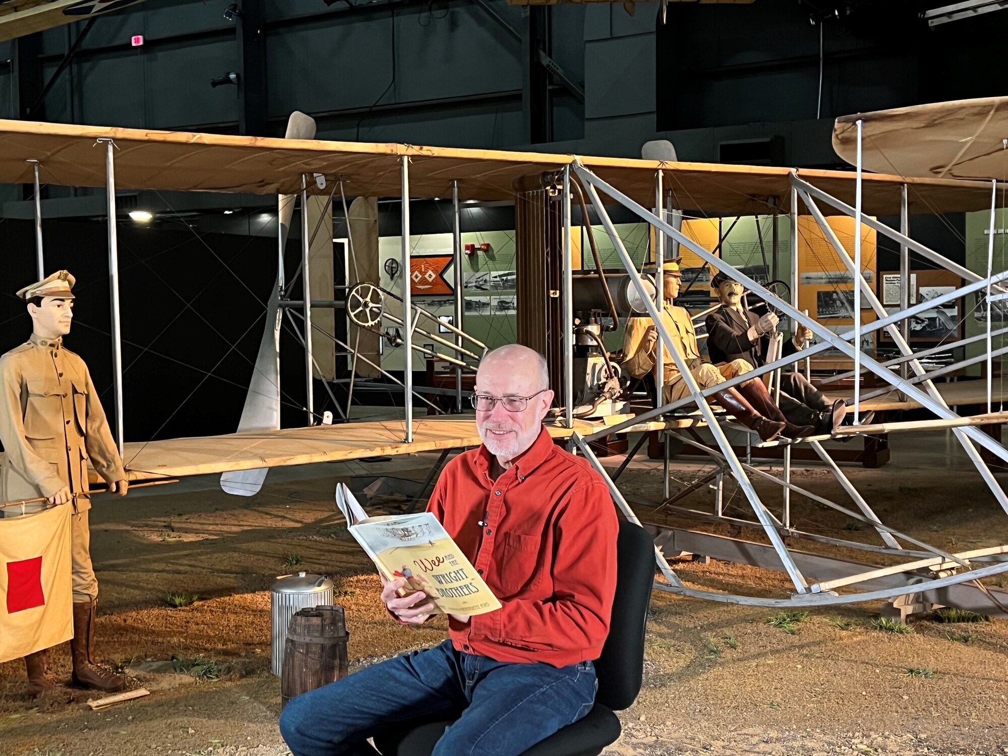 Guest reader sit in front of aircraft in the museum as they read books for virtual Read Across America.