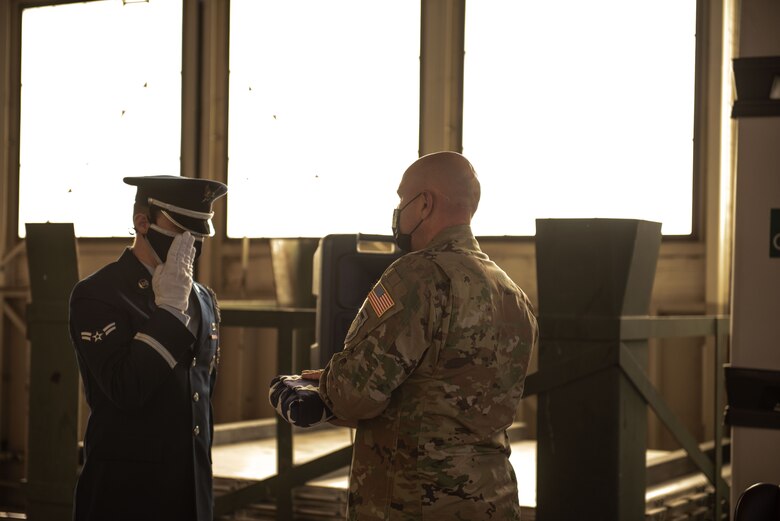 an honorguardsman presents the flag to the commander during a flag folding ceremony before a deployment