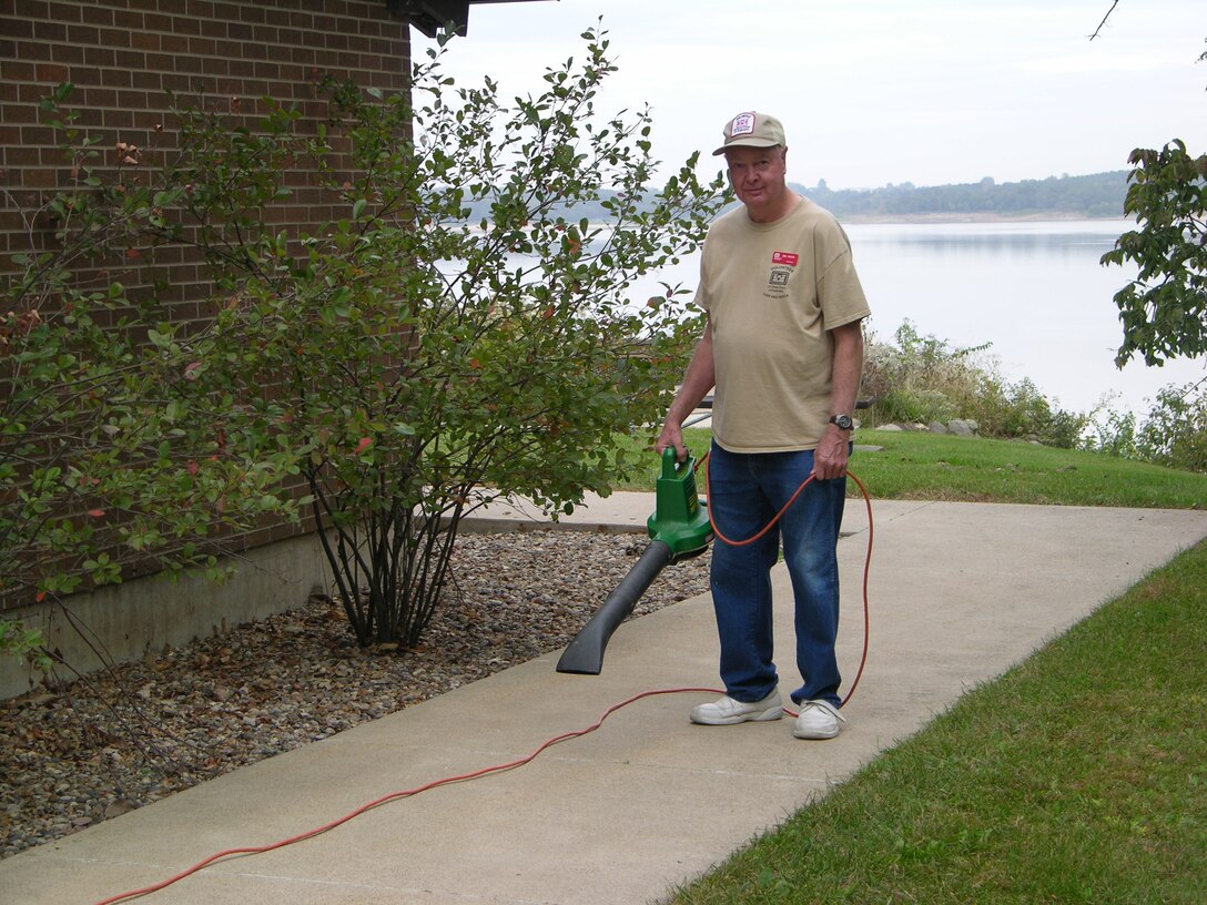 Volunteer cleaning sidewalk at visitor center