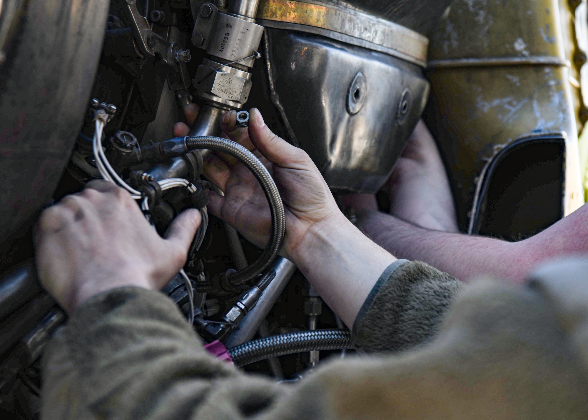 Close up photo of Airmens hands as they replace an engine on a B-52