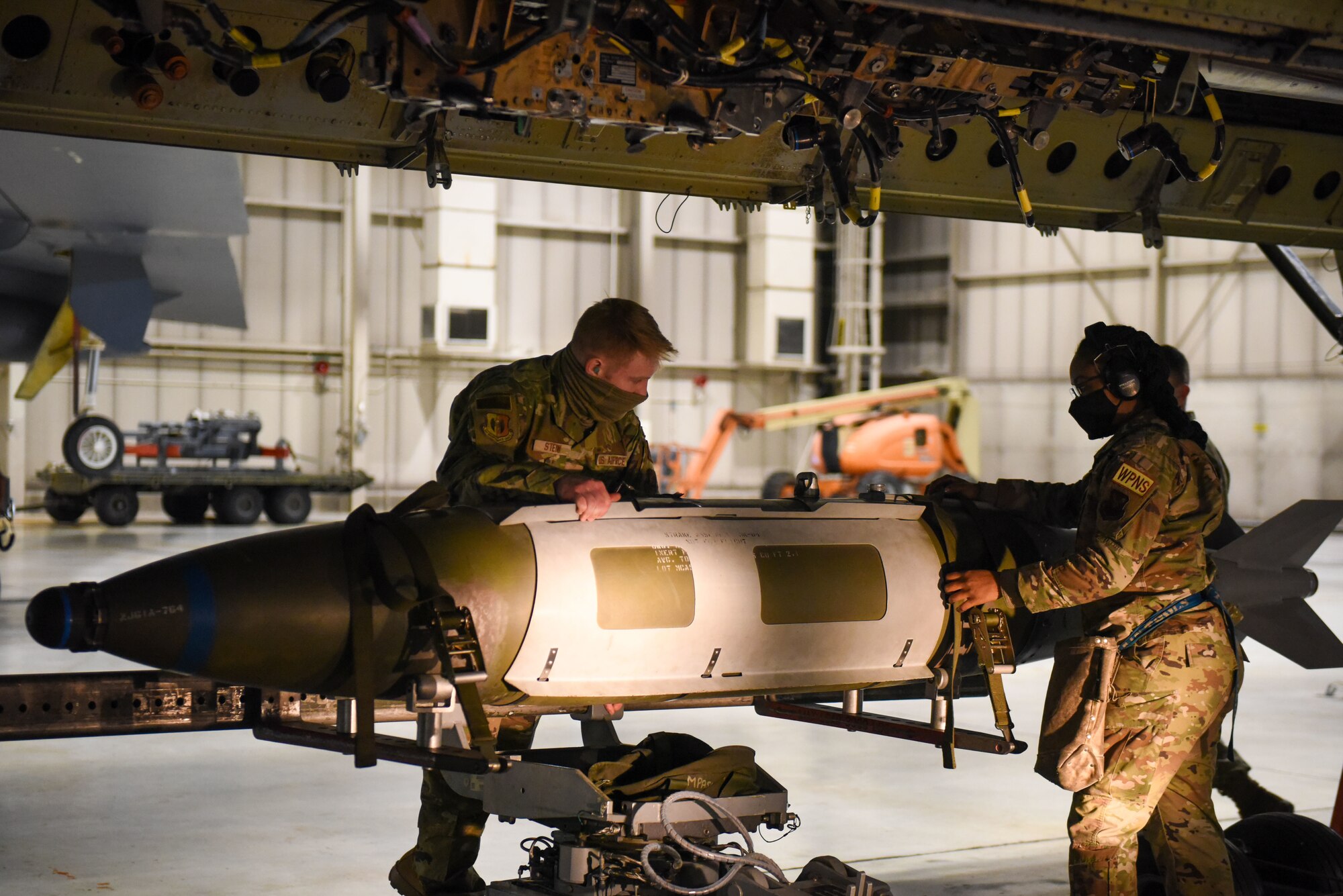 Two Airmen prepare a weapon to be loaded into the belly of a B-52