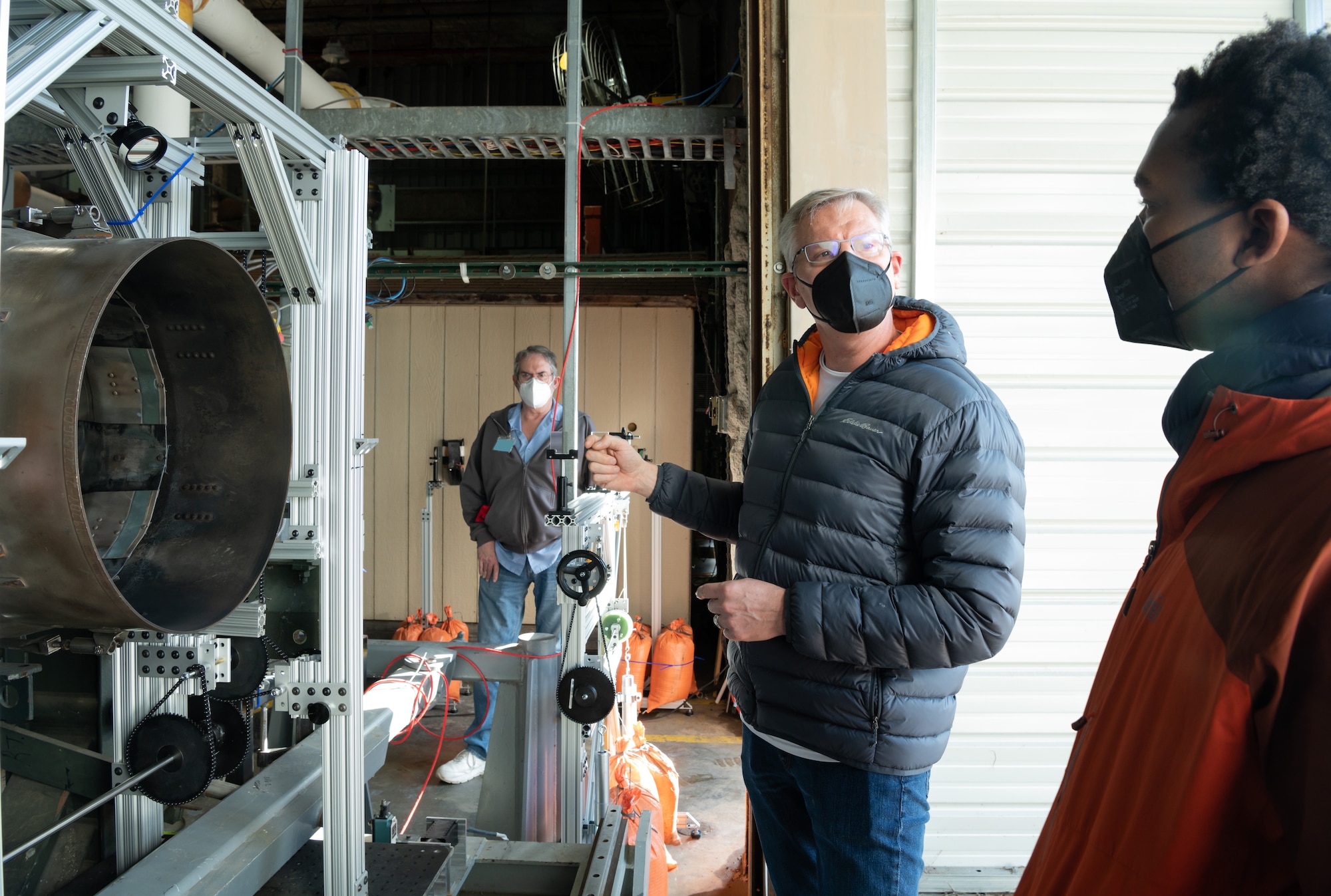 During a break in testing, Dr. Tom Jenkins, center, president of MetroLaser, Inc., explains to Dr. David Mayo, with the Naval Air Warfare Center Aircraft Division, how the cameras are adjusted to best capture the particulates of exhaust from an aircraft engine at the Propulsion Research Facility.