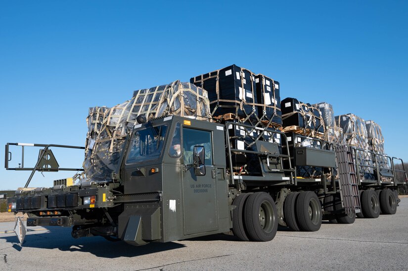 Pallets with cargo are atop a military truck.