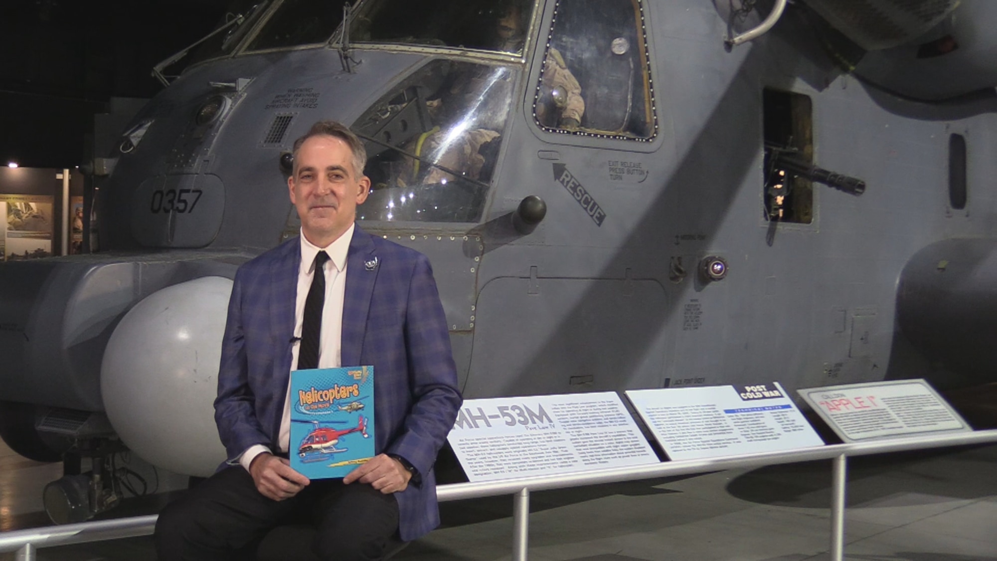 Guest reader sit in front of aircraft in the museum as they read books for virtual Read Across America.