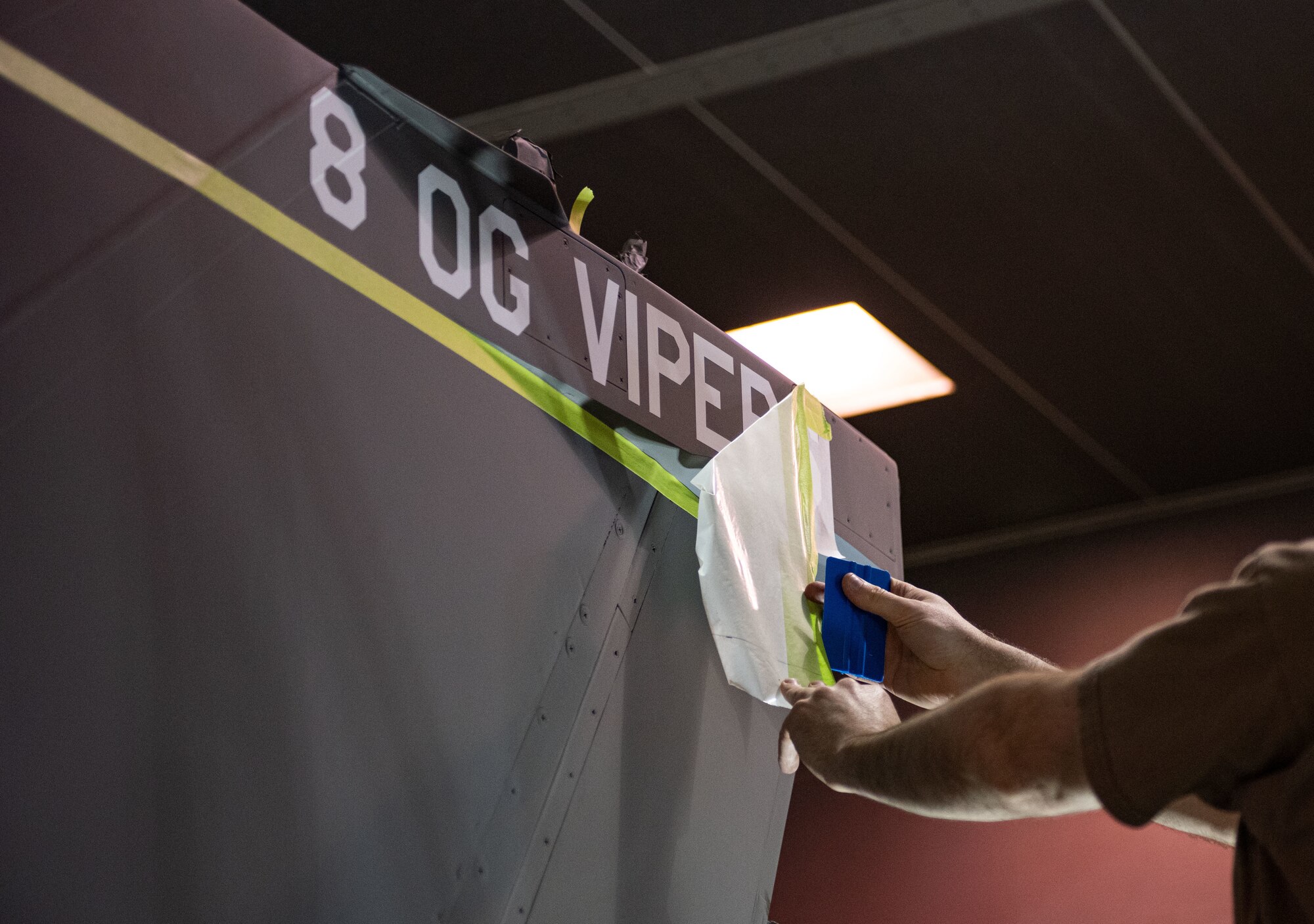 Tech. Sgt. David Lamb, 8th Maintenance Squadron noncommissioned officer in charge of aircraft structural maintenance, applies a stencil on an F-16 Fighting Falcon tail fin