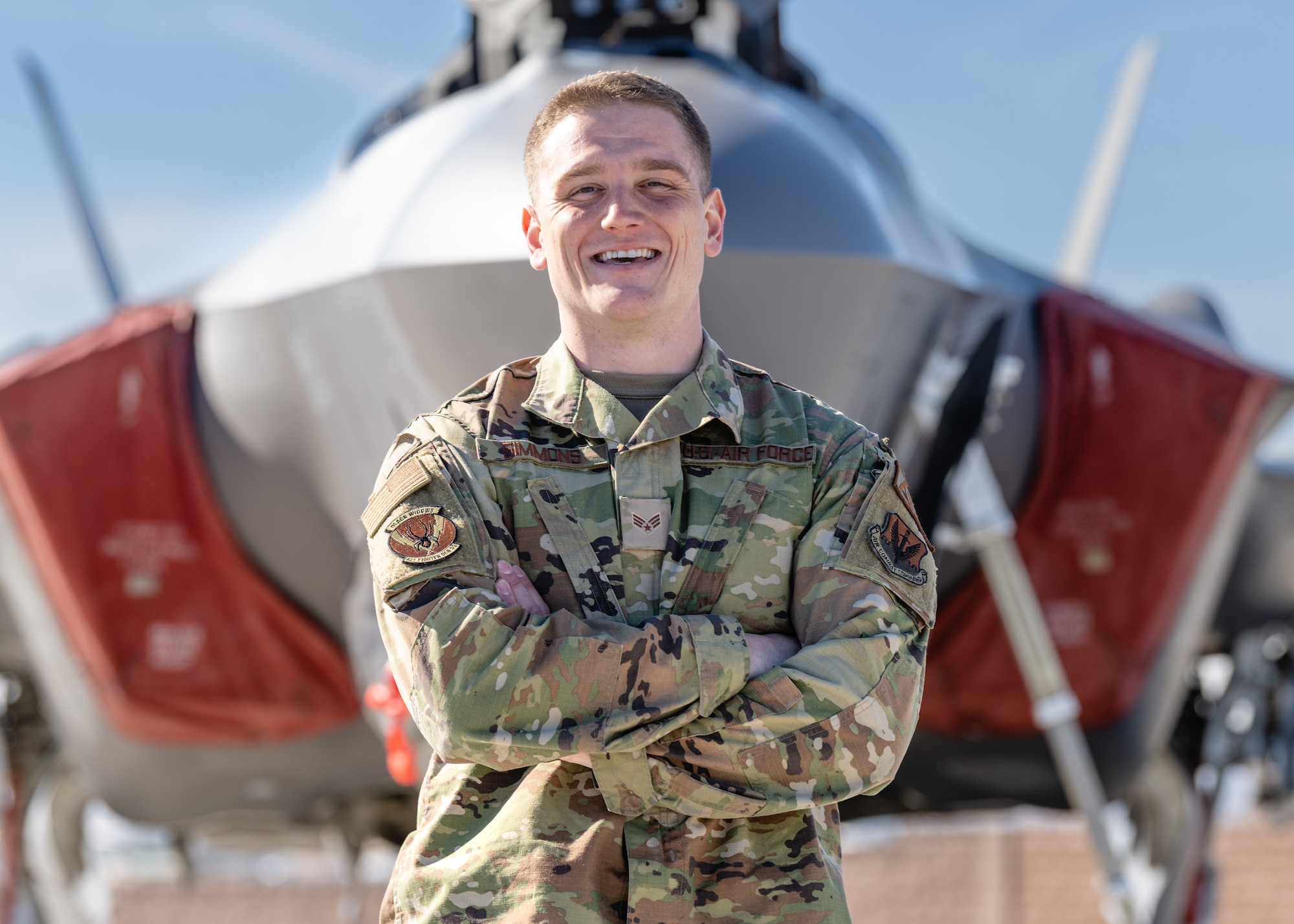 A photo of Senior Airman Erik Simmons standing in front of an F-35A fighter jet.