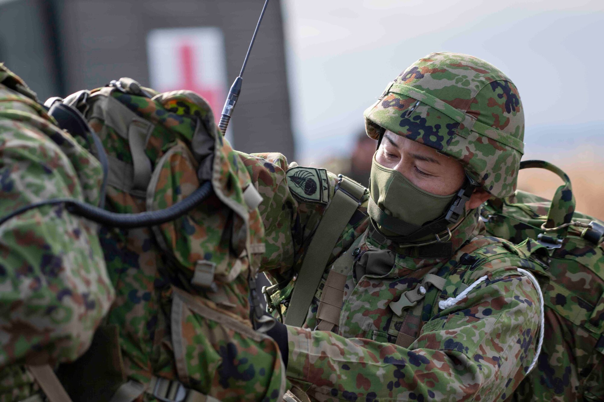 A Japan Ground Self-Defense Force paratrooper assigned to the 1st Airborne Brigade helps secure a backpack after completing an airborne jump from a U.S. Air Force C-130J Super Hercules assigned to the 36th Airlift Squadron at Combined Arms Training Center Camp Fuji, Japan, during Airborne 22, Jan. 25, 2022.