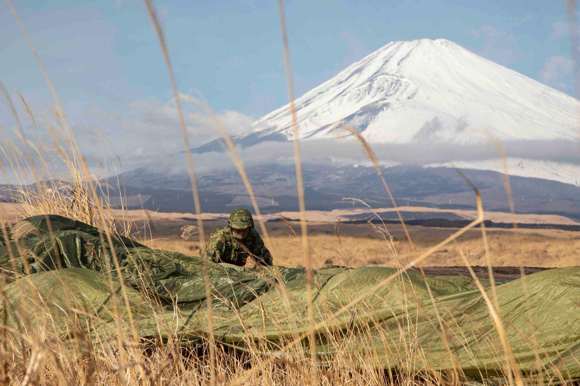 A Japan Ground Self-Defense Force paratrooper assigned to the 1st Airborne Brigade gathers his parachute after landing at the drop zone at Combined Arms Training Center Camp Fuji, Japan, Jan. 25, 2022, during Airborne 22.