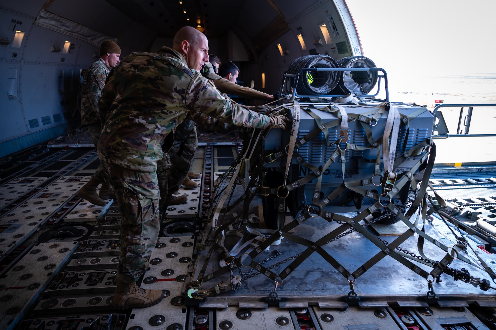 U.S. Air Force Chief Master Sgt. Sean M. Milligan, 332d Air Expeditionary Wing command chief, assists with moving cargo during the Command Chief’s immersion visit in Southwest Asia, Jan. 29, 2022. Chief Milligan's immersion visits give him a better understanding of the unique skillsets every Airman brings to the 332d AEW Red Tail team. (U.S. Air Force photo by Master Sgt. Christopher Parr)
