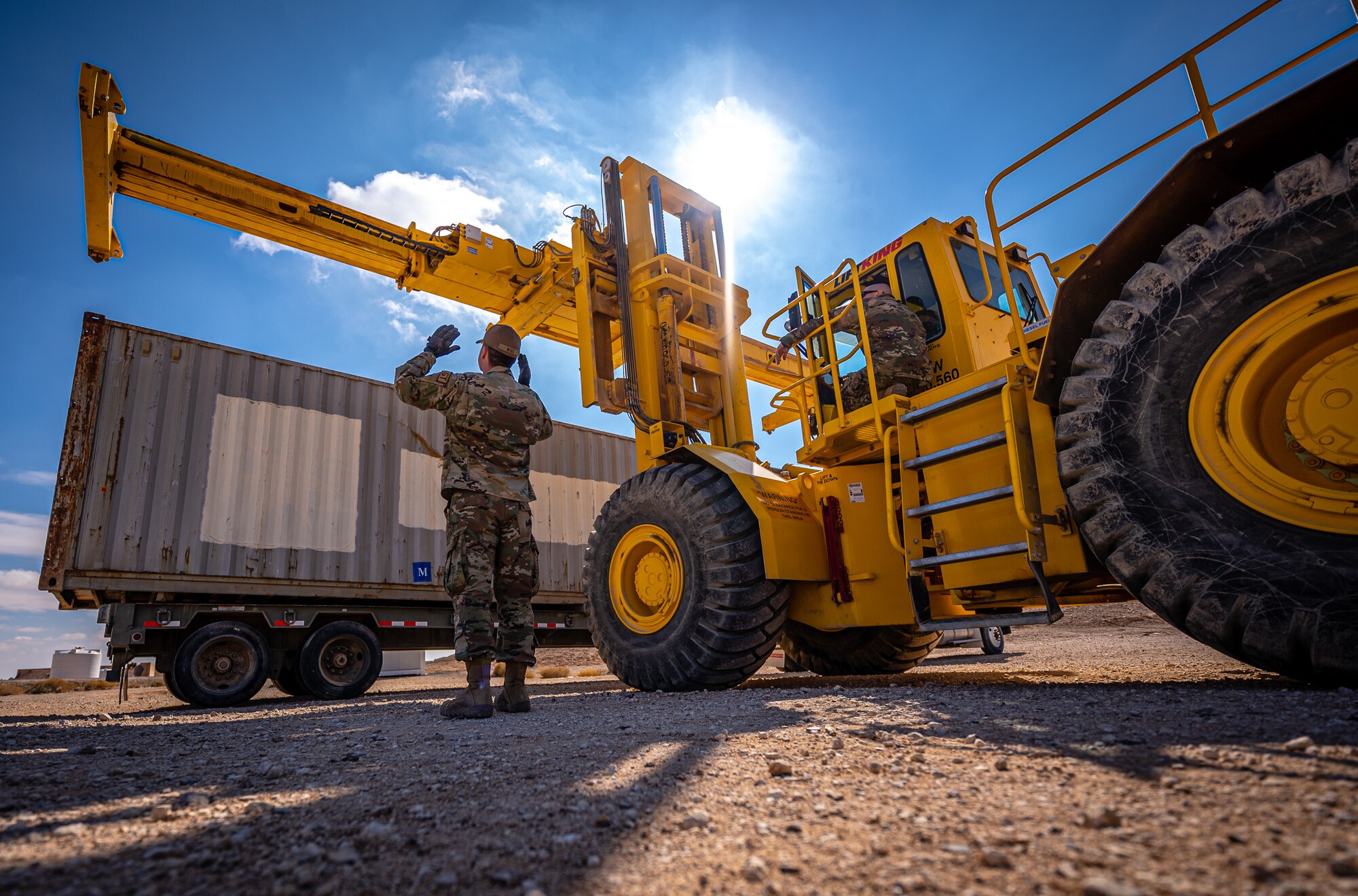A 332d Expeditionary Logistics Readiness Squadron Airman guides the Ruff Terrain Container Handler during a demonstration for Chief Master Sgt. Sean M. Milligan, 332d Air Expeditionary Wing command chief, during the Command Chief’s immersion tour in Southwest Asia, Jan. 29, 2022. Ruff Terrain Container Handlers are used by ground transportation to off-load shipping containers. Chief Milligan's immersion visits give him a better understanding of the unique skillsets every Airman brings to the 332d AEW Red Tail team. (U.S. Air Force photo by Master Sgt. Christopher Parr)