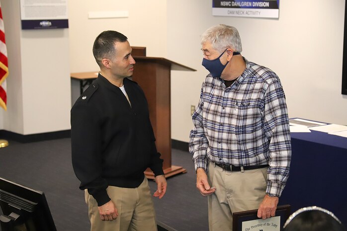 IMAGE: Randall Abbey, an Integrated Logistics Support Services technician at DNA, speaks to former commander Capt. Michael Aiena during an All Hands in Virginia Beach, Virginia, in December 2021. Abbey retired on Dec. 31, 2021, after 55 years of combined military and federal government service. He came to work at Naval Surface Warfare Center Dahlgren Division Dam Neck Activity in 1997 and is considered a plank owner—or one of the original members of the current organization.