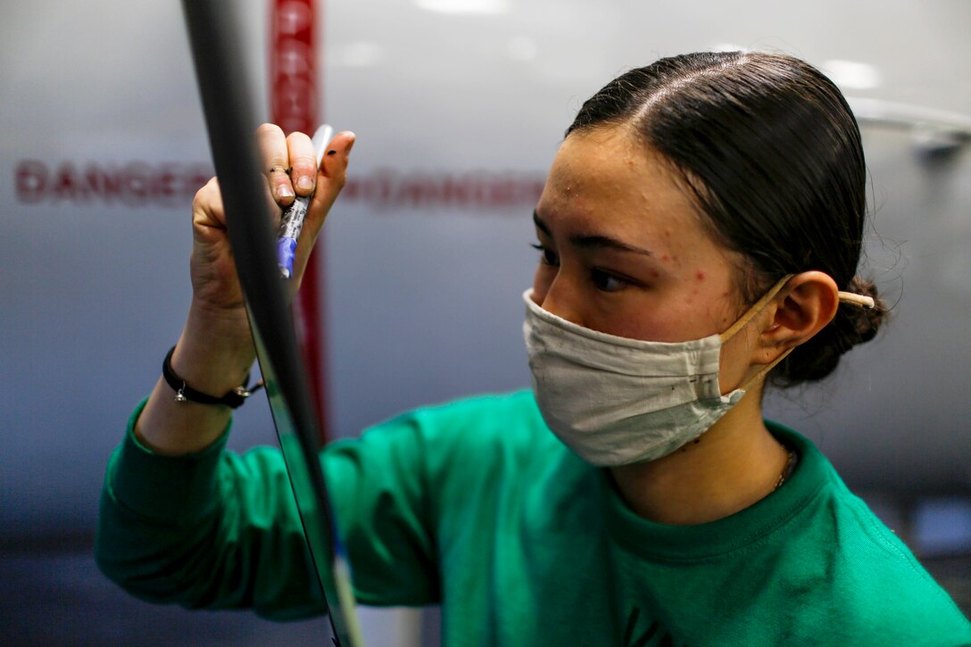 A sailor uses a tool to maintain a propeller.