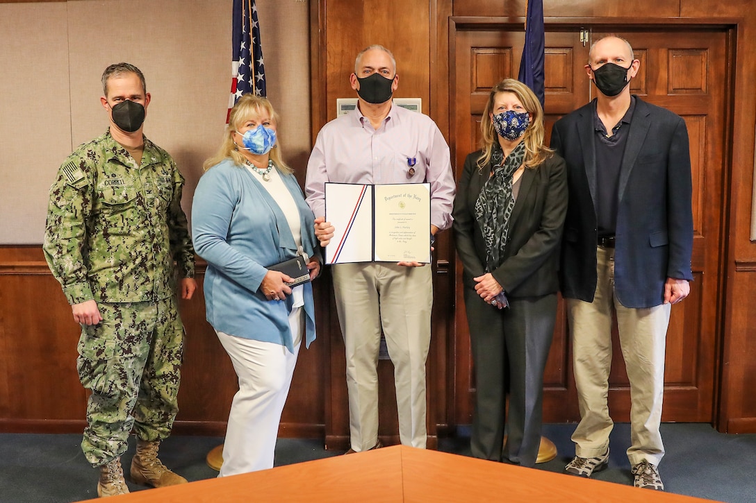 Group photo of John Hurley (center) being presented the Navy Meritorious Civilian Service Award